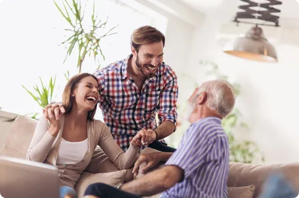 A family laughing together on a couch with an older man